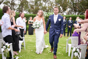 1 bride and groom walking down aisle under white rose petals in Melbourne