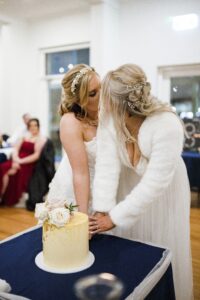 bride and bride kissing with cutting cake after sydney wedding