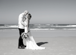 Black and white photo of bride and groom kissing on beach after New South Wales wedding