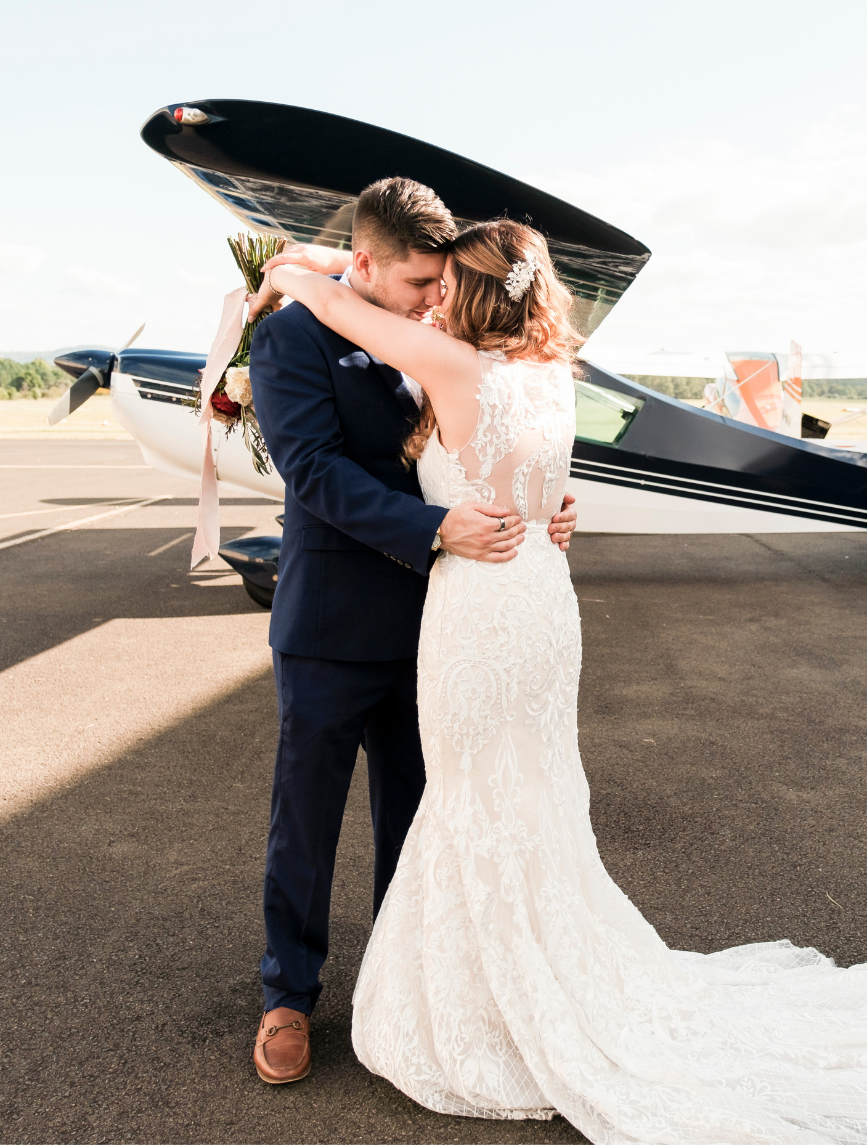 bride and groom posing for wedding photographer in front of plane at Camden Airport