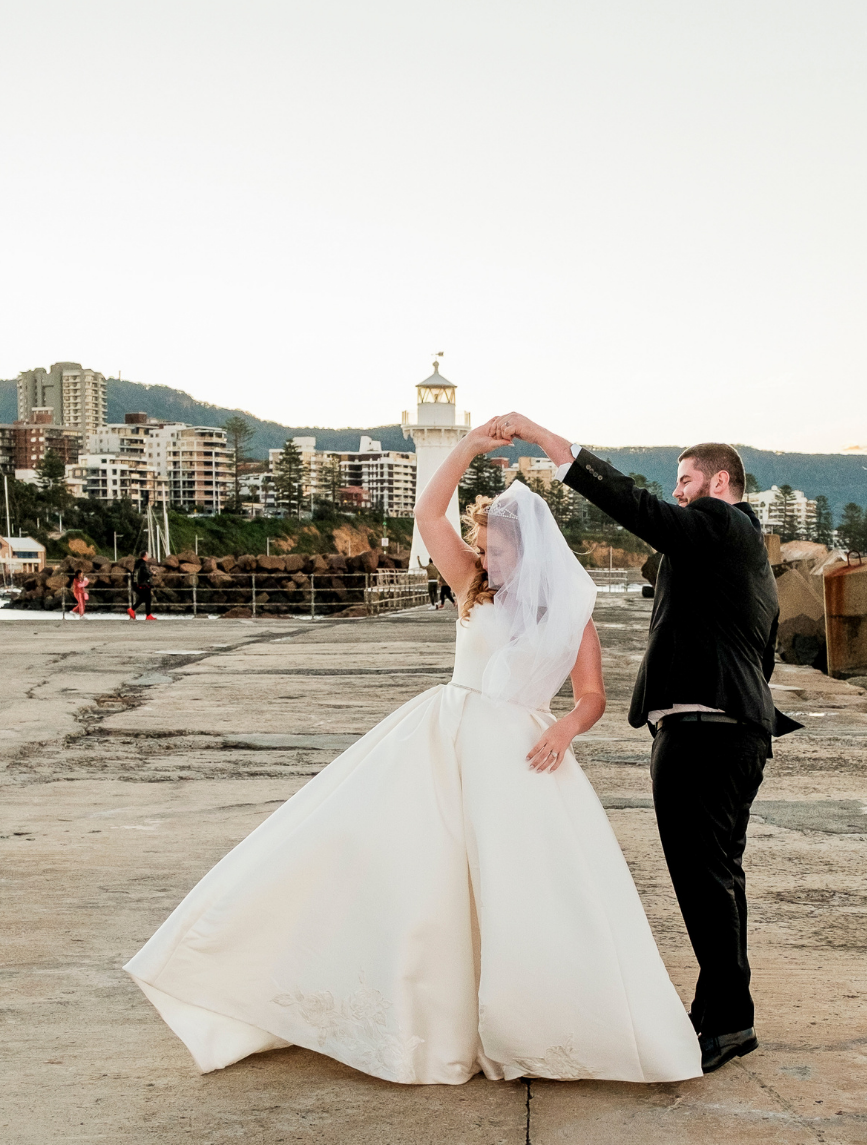 Bride and groom dancing at wollongong breakwater lighthouse
