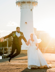 1 groom jumping at Wollongong lighthouse after wedding