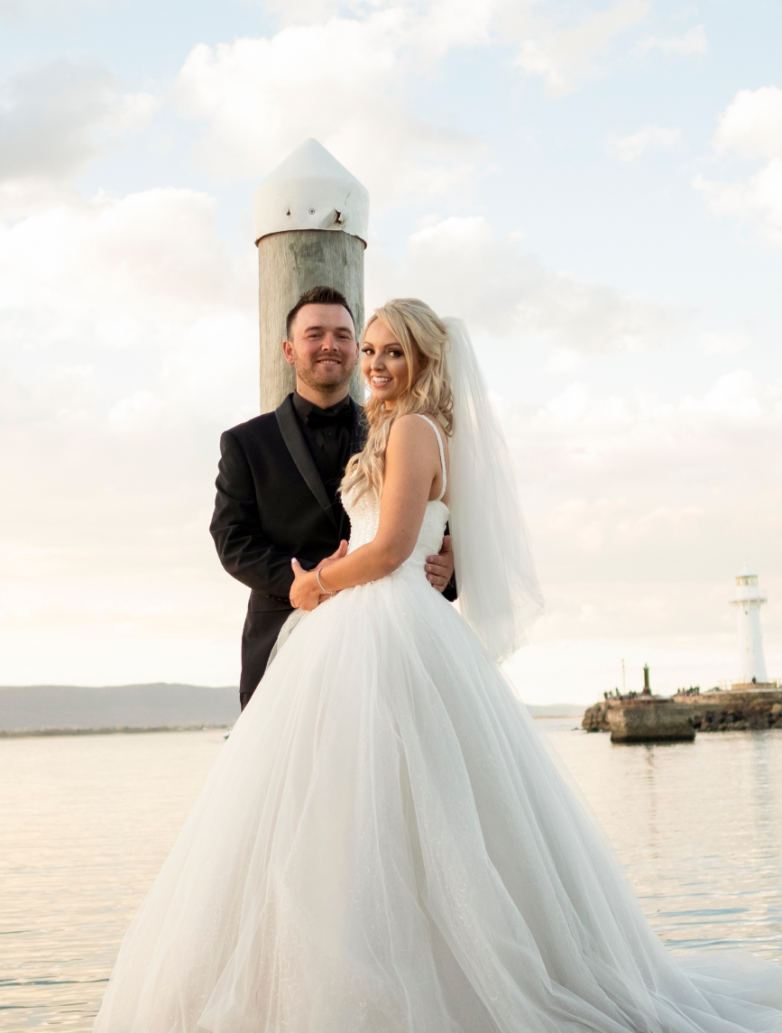 Jessica and Luke posing for wedding photographer on jetty in Wollongong New South Wales