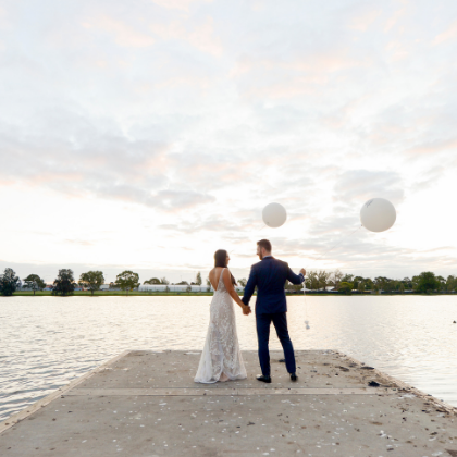 Bride and groom holding balloons on jetty after wedding in Melbourne