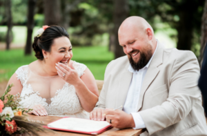 Bride and groom laughing while signing marriage certificate in central Sydney