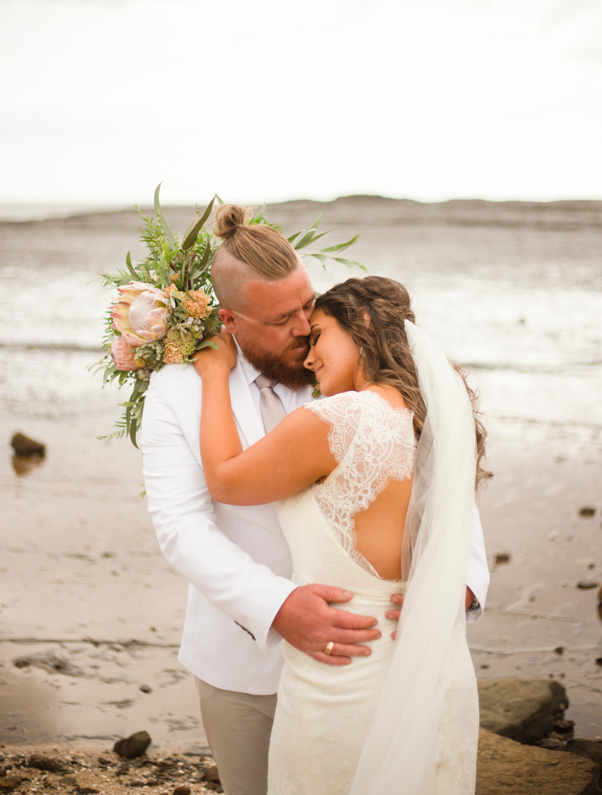 1 bride and groom hugging on beach