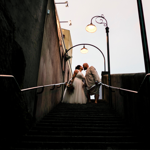 bride and groom kissing at top of stairs