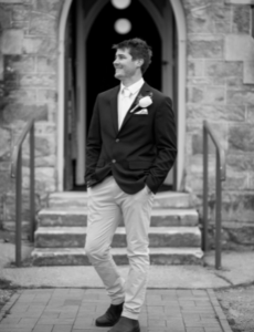 Black and white groom standing in front of church