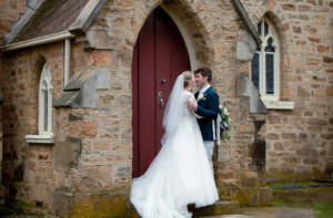bride and groom kissing in front of church door