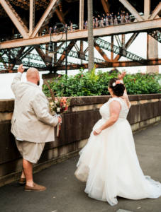 1 bride and groom waving at Sydney Harbour Bridge climbers