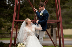 bride holding groom - groom climbing metal structure