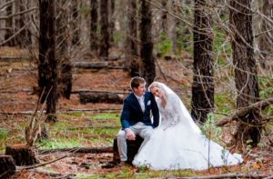 bride leaning on groom while sitting in forest in winter