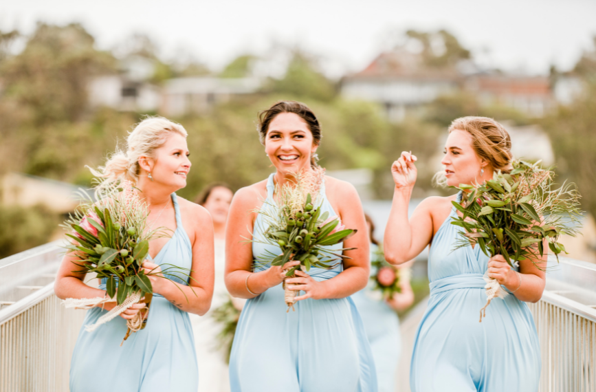 1 bridesmaids in blue dresses walking over bridge