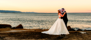 bride and groom kissing under veil at sunset