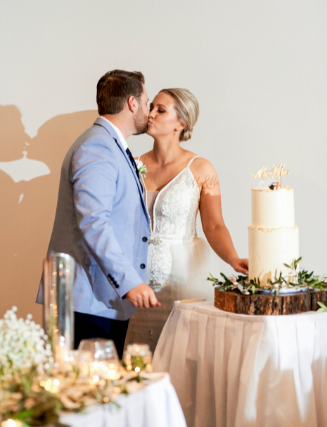 1 newlyweds kissing before cutting cake at wedding reception