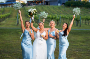 1 bride and bridesmaids posing for photographer with bouquets above heads