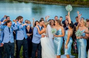 1 bride and groom kissing during group photo