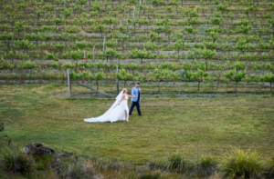 1 bride and groom walking through vineyards at ocean view estates wedding