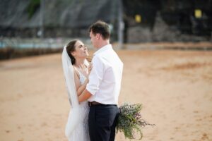 landscape image of bride and groom on bilgola beach after Sydney wedding