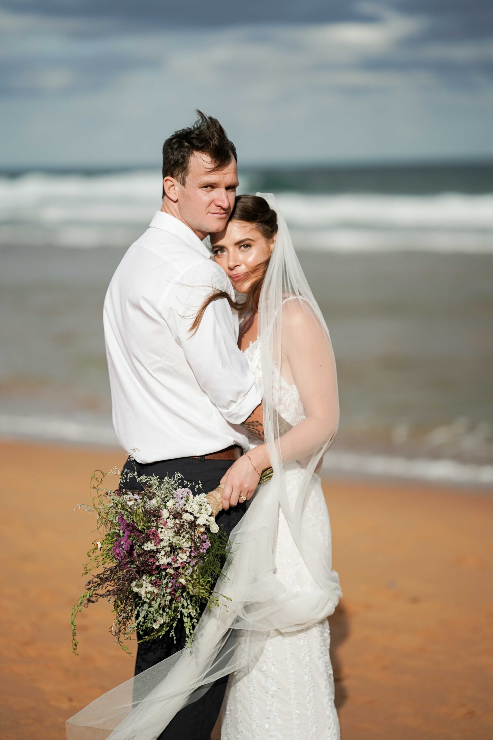 bride and groom posing for Sydney wedding photographer on beach
