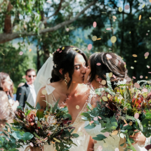 brides kissing under confetti at Log Cabin Ranch